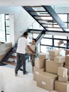 They make moving house look easy. Shot of a happy young couple passing boxes to each other while moving into their new