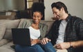 Were updating all our blogs today. Shot of a happy young couple using a laptop while relaxing on a couch in their living Royalty Free Stock Photo