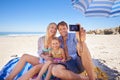 Smiling for a holiday pic. Shot of a happy young family taking a photo of themselves at the beach. Royalty Free Stock Photo