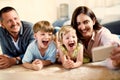 Dont need to ask kids twice to take a selfie. Shot of a happy young family taking selfies together at home. Royalty Free Stock Photo