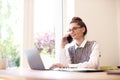 Attractive happy woman talking with somebody on her mobile phone while sitting behind laptop and working Royalty Free Stock Photo