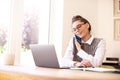 Attractive happy woman talking with somebody on her mobile phone while sitting behind laptop and working Royalty Free Stock Photo