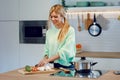 Healthy young woman cutting fresh vegetables while cooking healthy food in casserole in the kitchen at home Royalty Free Stock Photo