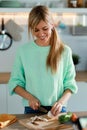 Healthy young woman cutting fresh vegetables while cooking healthy food in casserole in the kitchen at home Royalty Free Stock Photo