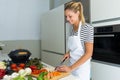 Healthy young woman cutting fresh vegetables in the kitchen at home. Royalty Free Stock Photo