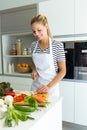 Healthy young woman cutting fresh vegetables in the kitchen at home. Royalty Free Stock Photo