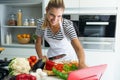 Healthy young woman cutting fresh vegetables and using digital tablet to recipes in the kitchen at home. Royalty Free Stock Photo