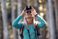 Hiker young woman looking birds through binoculars telescope in forest Royalty Free Stock Photo