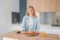 Portrait of a hungry young woman eating wholesome sandwich, having tasty breakfast in a kitchen at home in the morning Royalty Free Stock Photo