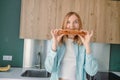 Portrait of a hungry young woman eating wholesome sandwich, having tasty breakfast in a kitchen at home in the morning Royalty Free Stock Photo