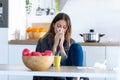 Illness young woman sneezing in a tissue while sitting in the kitchen at home