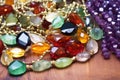 shot of jumbled necklace chains next to a pile of loose gemstones Royalty Free Stock Photo