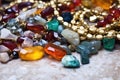 shot of jumbled necklace chains next to a pile of loose gemstones Royalty Free Stock Photo