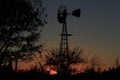 Kansas Sunset with a Windmill and tree silhouettes out in the country north of Hutchinson Kansas USA.