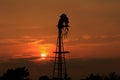 Kansas Windmill Silhouette with a Blazing orange Sunset with the Sun and Sky.