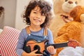 Its my favourite thing to play with. Shot of a little boy playing the guitar while sitting at home. Royalty Free Stock Photo
