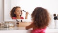 Im gonna look just like my mommy. Shot of a little girl applying blusher in the mirror.