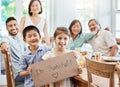 Whoever you are, you need family. Shot of a little girl holding a sign while having lunch at home. Royalty Free Stock Photo