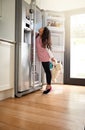 Searching for a snack. Shot of a little girl reaching for something in the fridge at home. Royalty Free Stock Photo