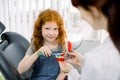 Shot of a little smiling pretty shool girl with bright red curly hair, sitting in dental chair and cleaning the teeth Royalty Free Stock Photo
