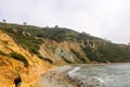 A shot of the lush green and red rock mountain landscape and the rocky beach and the ocean with waves crashing against the rocks Royalty Free Stock Photo