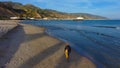 Man with a backpack walking along the beach with blue ocean water Royalty Free Stock Photo