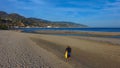 Man with a backpack walking along the beach with blue ocean water Royalty Free Stock Photo