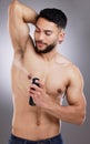 Ladies love a man that smells good. Shot of a man spraying deodorant into his armpits against a studio background. Royalty Free Stock Photo