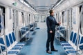 Shot of man who doesnt work at distance during quarantine, wears face mask to avoid coronavirus infection, poses in empty Royalty Free Stock Photo