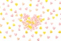 Many multi-colored marshmallows in the shape of hearts are scattered randomly. Festive background