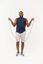 Shot of masculine man skipping rope. Muscular young man exercising with jumping rope against grey background