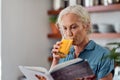 Its not a diet, its a way of life. Shot of a mature woman reading a book while having orange juice at home. Royalty Free Stock Photo