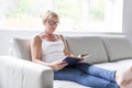 Shot of a mature woman reading her favorite novel while at home in living room. Royalty Free Stock Photo