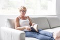 Shot of a mature woman reading her favorite novel while at home in living room. Royalty Free Stock Photo