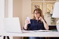 Shot of middle aged woman using mobile phone and text messaging while working from home Royalty Free Stock Photo