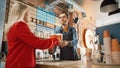 Shot in Modern Hipster Cafe: Handsome Smiling Barista in Checkered Shirt Passes Cardboard Cupholde