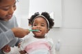 Mom will help her keep her baby teeth clean. Shot of a mother brushing her little daughters teeth in the bathroom at