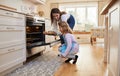 Be careful its very hot. Shot of a mother and daughter inserting a tray of cupcakes into the oven. Royalty Free Stock Photo