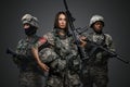 Tattooed female soldier with rifle near her two comrades