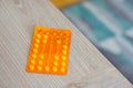 Shot of an orange pile of medical tablets on a wooden surface