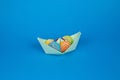 Shot of an origami paper ship full of tasty marmalade candies on a pastel blue background