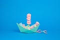 Shot of an origami paper ship full of tasty marshmallows on a pastel blue background