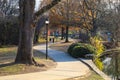 A shot of people walking along a smooth winding footpath in the park near a lake surrounded by gorgeous autumn colored trees