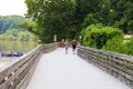 People walking down the boardwalk along the Chattahoochee river with vast silky brown river water surrounded by lush green trees