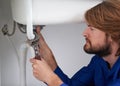 No plumbing problem is too big or small for him. Shot of a plumber repairing a pipe underneath a sink.