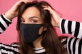 Shot portrait of young brunette attractive woman wearing mediacal face mask over background wall. Protection