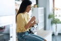 Pretty happy young woman eating yogurt while smiling thinking on her things sitting on the kitchen at home Royalty Free Stock Photo