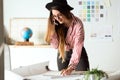 Pretty young architect woman working on a blueprints while talking on the phone in the office. Royalty Free Stock Photo