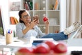 Pretty young business woman using her mobile phone while eating red apple in the office Royalty Free Stock Photo