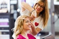 Pretty young hairdresser making hairstyle to cute woman in the beauty salon. Royalty Free Stock Photo